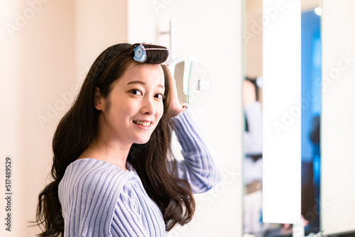 鏡の前で髪のセットをする若い女性 photo