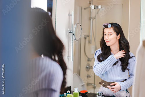 鏡の前で髪のセットをする若い女性
