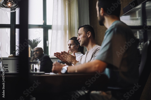 Mature businessman gesturing while sharing ideas with colleagues in meeting room photo