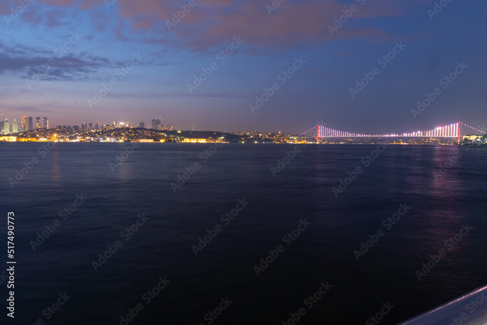 Panorama of Istanbul at night, long exposure with silky water and Basques in movement, the tall buildings of the city can be seen, and the Bosphorus bridge