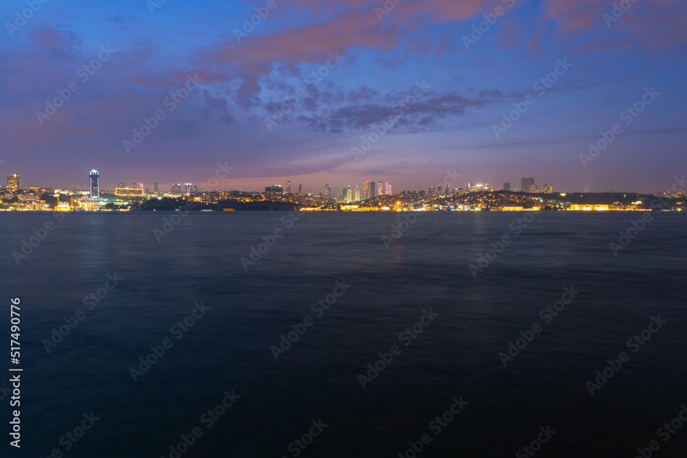 Panorama of Istanbul at night, long exposure with silky water and basques in movement, the tall buildings of the city are observed.