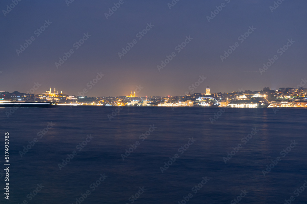 Panorama of Istanbul at night, long exposure with silk water and basques in movement, the mosques and the Galata tower are observed.