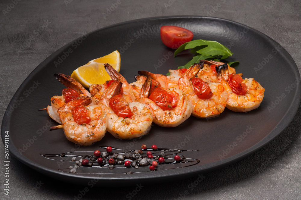 grilled shrimp on a skewer with tomatoes on a dark plate grilled shrimp on a skewer with tomatoes on a dark plate