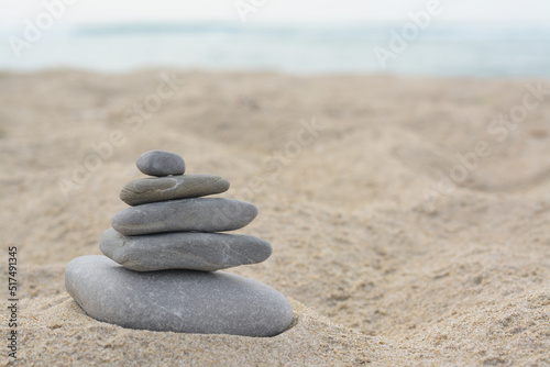 Stack of stones on sandy beach near sea  space for text