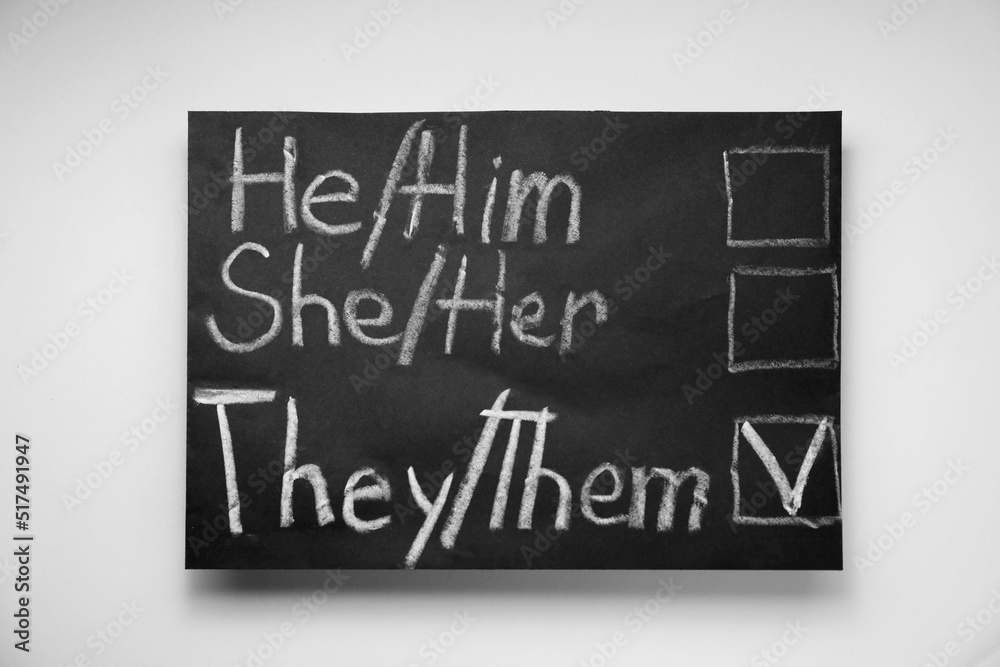 Fototapeta premium Gender equality. Small blackboard with written pronouns on beige background, top view