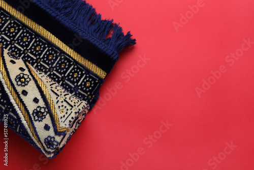 Muslim prayer rug on red background, top view. Space for text