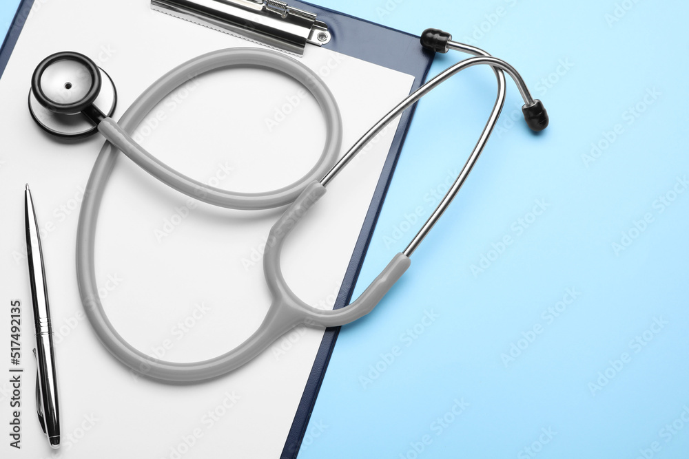 Clipboard with stethoscope and pen on light blue background, top view. Space for text Clipboard with stethoscope and pen on light blue background, top view. Space for text