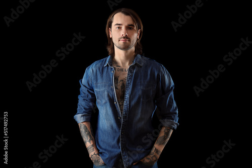 Young man with tattoos on body against black background