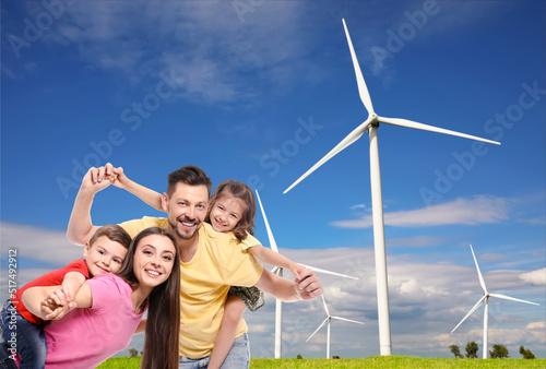 Happy family with children and view of wind energy turbines on sunny day © New Africa