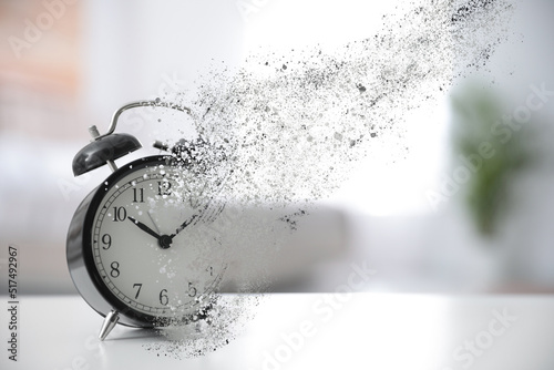 Time is running out. Black alarm clock vanishing on table in room