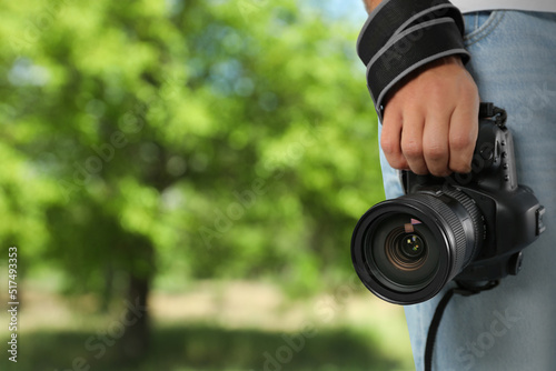 Professional photographer with modern camera and blurred view of park, space for text