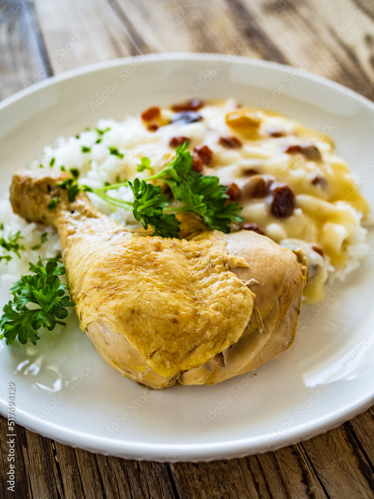Boiled chicken thigh with white rice and lemon creamy sauce with raisins on wooden table