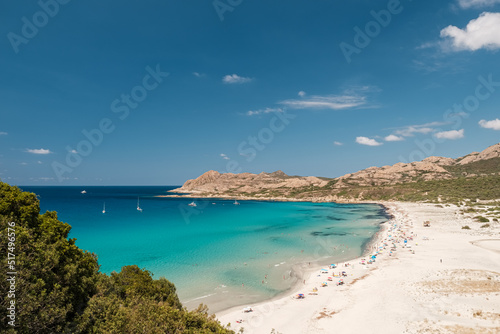 Holidaymakers enjoying the sunshine and turquoise Mediterranean sea in the Balagne region of Corsica with the rocky coast of Desert des Agriates behind © Jon Ingall