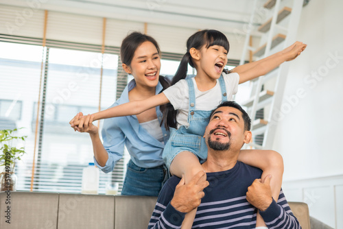 Happy dad lifting excited daughter girl playing airplane with flying open hand in living room.Asian family home entertainment concept.