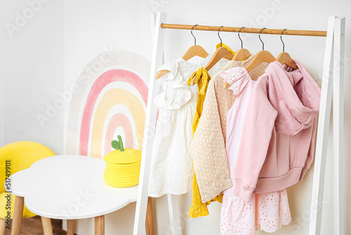 Wooden Clothing Rack with children's dress in kids room. Montessori wardrobe. Nursery Storage Ideas. Baby Girl Clothes.