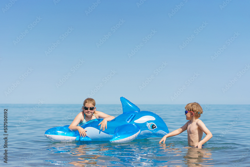 Kids are playing the sea. Little baby boys and girl in goggles with inflatable toy float shark and dolphin playing in the water on summer vacation. Babyproof on the beach and sea