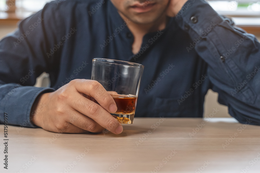 drunk man holding whiskey glass on the table