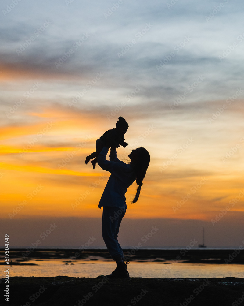Silhouette of a mother with a child on the coast of the ocean