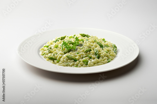 Risotto with green asparagus and parsley in white plate