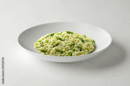 Risotto with green asparagus in white bowl