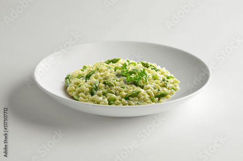 White bowl of risotto with green asparagus and parsley