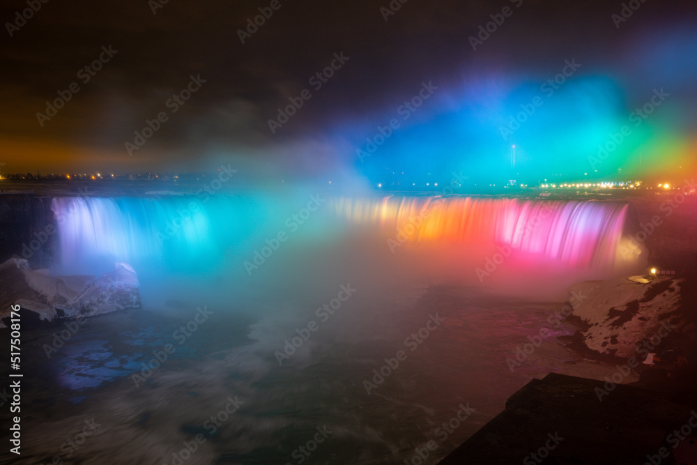Naklejka premium Night illumination on Horseshoe Falls at Niagara Falls Canada are pouring water through frozen landscape at winter