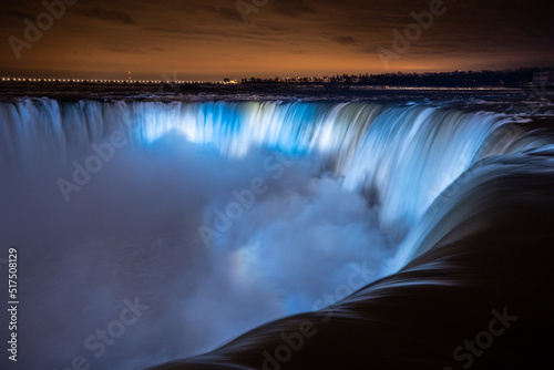 Night illumination on Horseshoe Falls at Niagara Falls Canada are pouring water through frozen landscape at winter