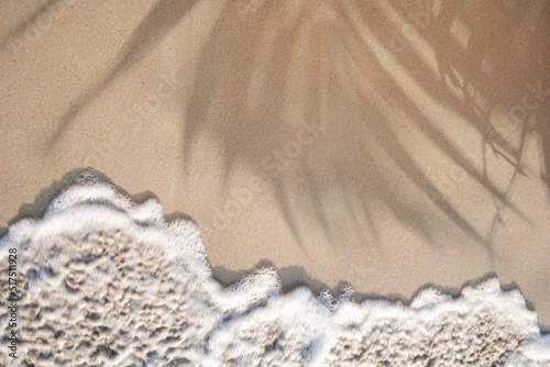 Fototapeta Naklejka Na Ścianę i Meble -  Soft ocean wave on a tropical sandy beach with palm leaves shadow in the summer