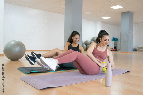 TWO GIRLS TRAINING YOGA AND PILATES TOGETHER WITH A BALL AND WEIGHTS