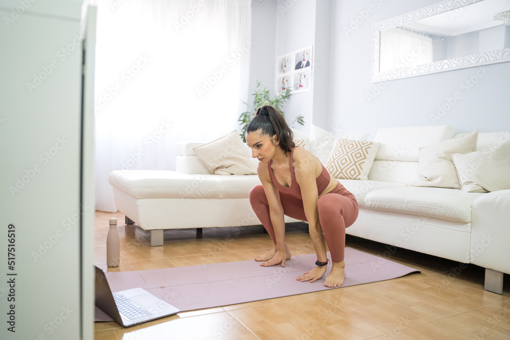 YOUNG GIRL DOING YOGA AND PILATES IN THE LIVING ROOM OF HER HOME WITH THE COMPUTER YOUNG GIRL DOING YOGA AND PILATES IN THE LIVING ROOM OF HER HOME WITH THE COMPUTER