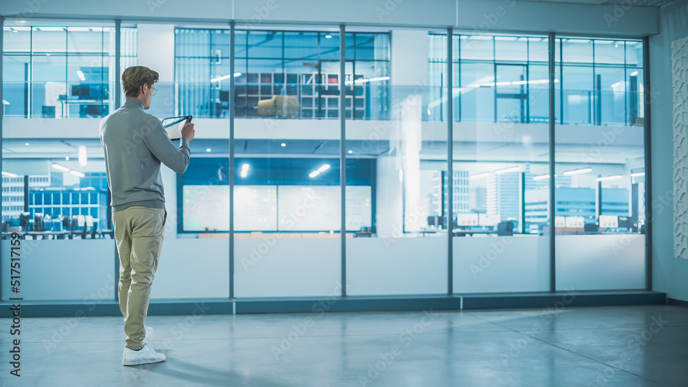 Obraz premium Handsome Stylish Interior Designer Standing in Empty Modern Office and Taking Measurments with an Augmented Reality Software on a Tablet Computer. Business Company Space Under Renovation Process.