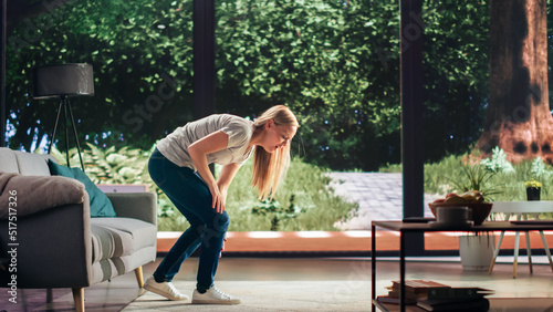 Принти на полотні Young Adult Female Standing Up from a Couch at Home and Experiencing Discomfort in a Result of Leg Trauma or Arthritis