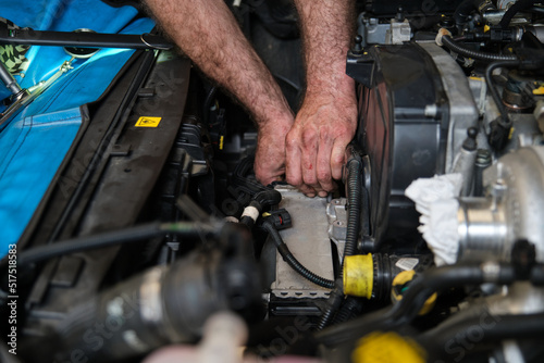 Car mechanic hands replacing intercooler on a car engine. Mechanics workshop.