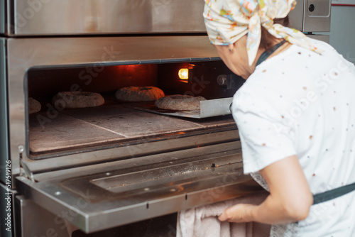 baker puts the bread dough in the oven