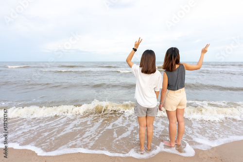 Young couples prefer Asian women who are tourists. walking along the beach which the waves crashed with a cheerful expression on her holiday evening atmosphere sunset photo