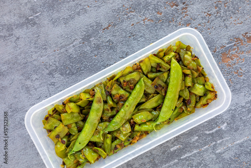 Sugar peas vegetable dish in plastic container. Sugar peas poriyal (sugar peas thoran) Asian cuisine style meal. photo