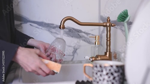 Woman wash up dishes with soap foam and sponge in kitchen sink at home.