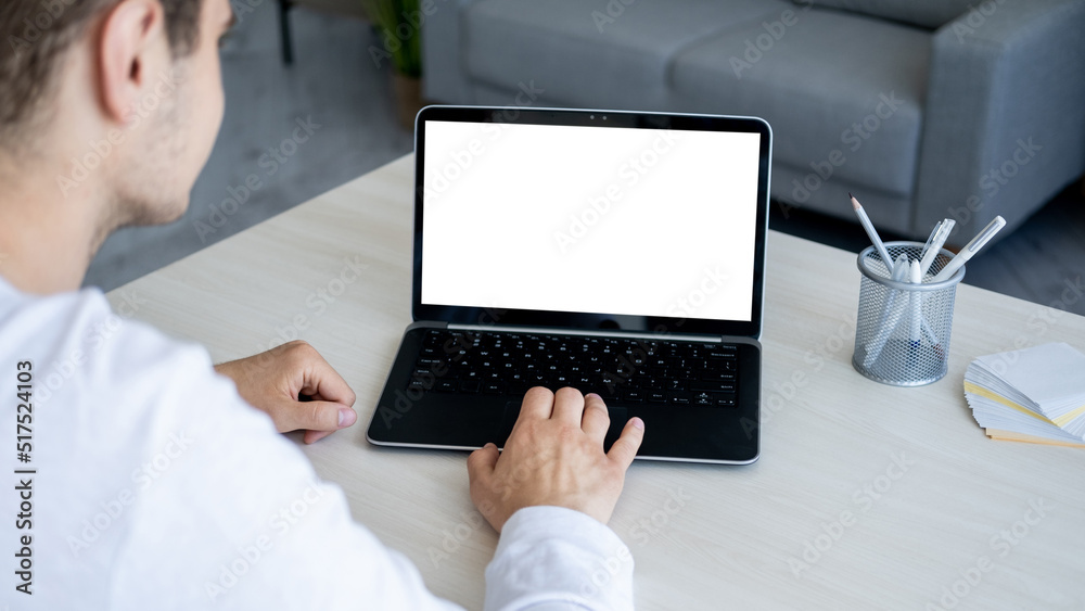 Online conference. Distance work. Computer mockup. Unrecognizable man sitting desk with laptop blank screen in light room interior. Online conference. Distance work. Computer mockup. Unrecognizable man sitting desk with laptop blank screen in light room interior.