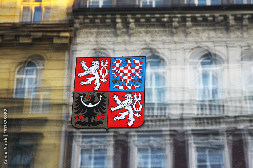 Naklejka premium Coat of arms of the Czech Republic on the glass and historical buildings are reflected