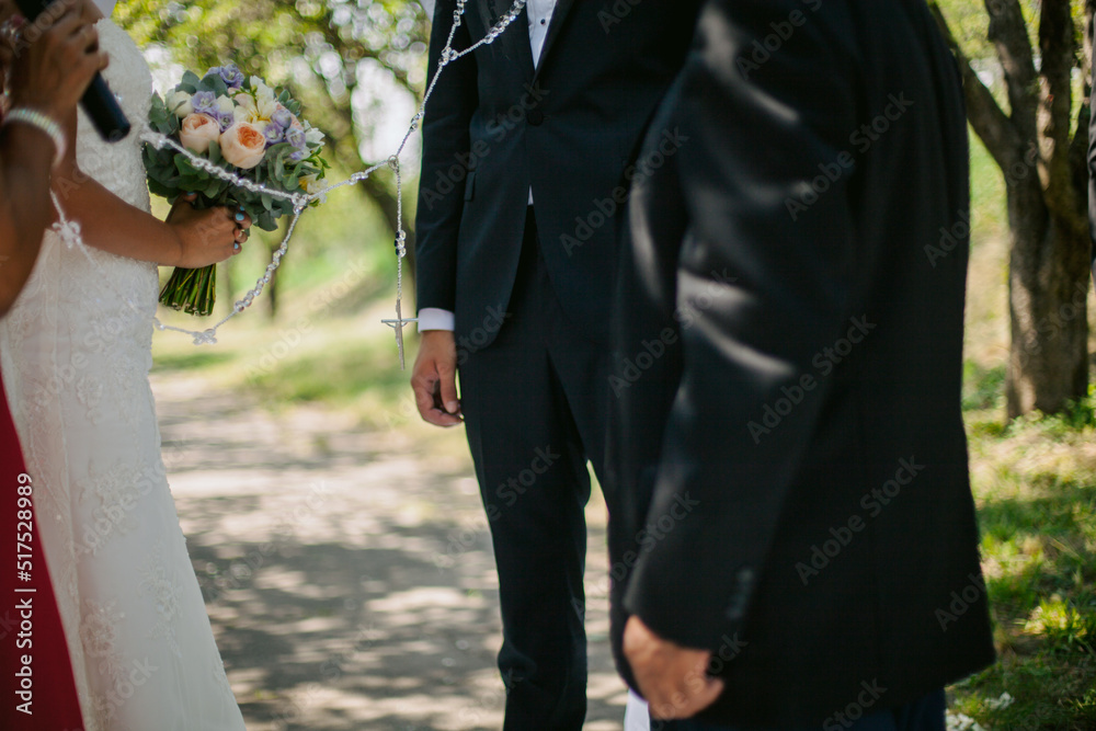 newlyweds are standing at the wedding arch, they are wearing a chain ...