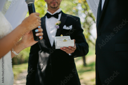 The newlyweds exchange rings, near the wedding arch, at the wedding ceremony. wedding rings and the hands of the bride and groom. young wedding couple at ceremony. marriage. soft focus photo