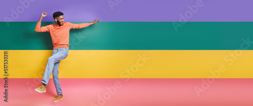 Full length of playful African man dancing against colorful background
