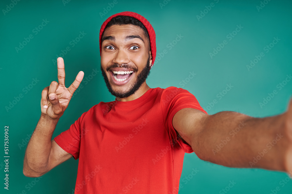 Excited African man gesturing while making selfie against green background Excited African man gesturing while making selfie against green background
