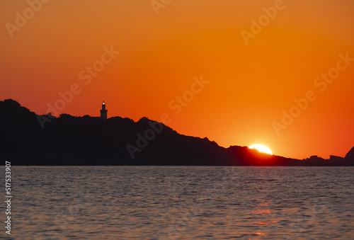 The sun at sunset behind the lighthouse and cape Higer, Euskadi photo