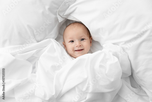 Happy newborn baby peeking from white sheet photo