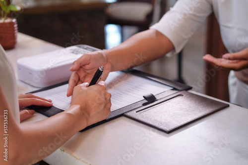 Close up of hand filling up the form or signing document. Bank loan, financial deal, medical insurance or hotel registration
