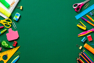 Frame of colorful school supplies on green table. Back to school concept. Top view. Flat lay.
