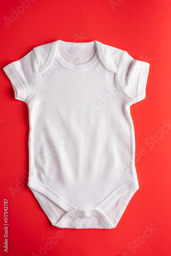 Flat lay mockup of white cotton bodysuit for little girls on red background. Layout, template for design and separation of prints, logos, advertising. There are no people in the photo.