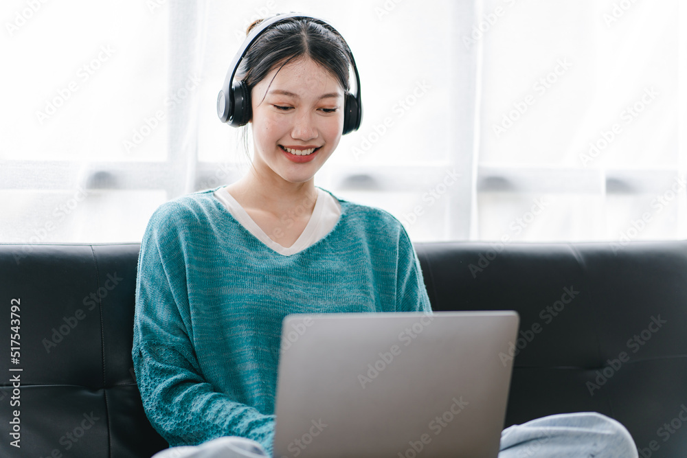 Smart and positive Asian female freelancer or female college student sitting on sofa with laptop. Study from online webinars or home courses. Video calling and chatting Smart and positive Asian female freelancer or female college student sitting on sofa with laptop. Study from online webinars or home courses. Video calling and chatting