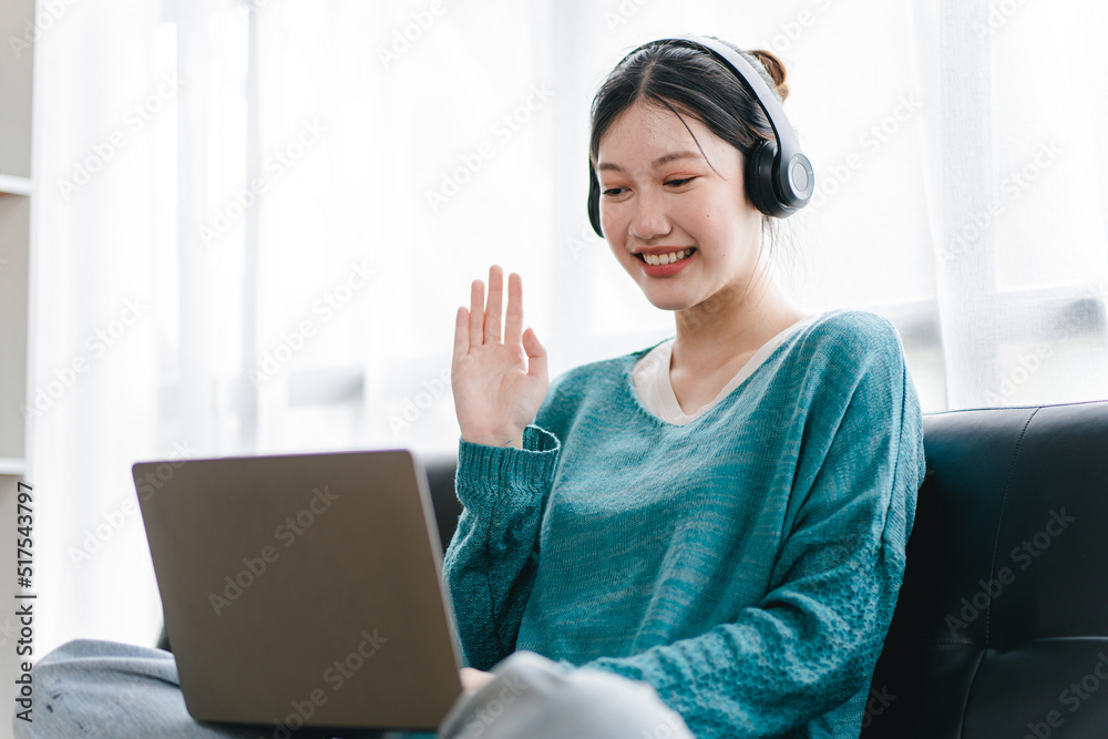 Smart and positive Asian female freelancer or female college student sitting on sofa with laptop. Study from online webinars or home courses. Video calling and chatting Smart and positive Asian female freelancer or female college student sitting on sofa with laptop. Study from online webinars or home courses. Video calling and chatting